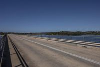 a man riding a horse on top of a bridge next to water under a blue sky