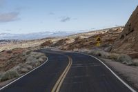 a wide open road in the middle of mountains and snow capped mountain tops in the distance