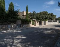 an open road and building are behind a stone fence with ivys on the front