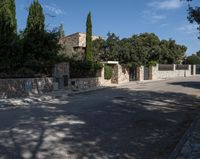 an open road and building are behind a stone fence with ivys on the front