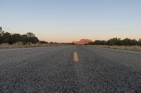 a long empty road with mountains in the distance with a car in the foreground