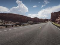 a paved desert road in the middle of nowhere, with mountain peaks behind it and an open road