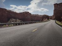 a paved desert road in the middle of nowhere, with mountain peaks behind it and an open road