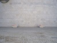 there are several benches sitting in front of this wall that is a large round stone block