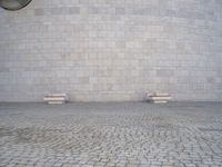 there are several benches sitting in front of this wall that is a large round stone block