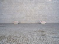 there are several benches sitting in front of this wall that is a large round stone block