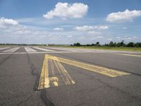 the street is paved with yellow lines that make it difficult to cross the runway for pedestrians