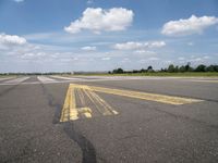 the street is paved with yellow lines that make it difficult to cross the runway for pedestrians