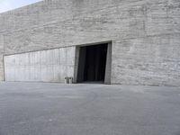 the view from the street through an entrance into a large building with concrete walls on both sides