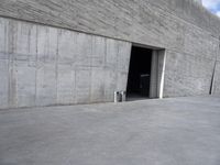 the view from the street through an entrance into a large building with concrete walls on both sides