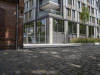 modern glass office building on brick streets corner with stairs leading up and a brick block walkway