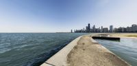 chicago skyline with a concrete walkway stretching into the water along the shore of lake michigan