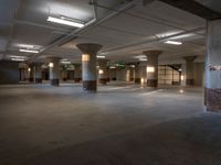 an empty office with columns and light coming in from them, with some lights on