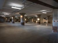 an empty office with columns and light coming in from them, with some lights on