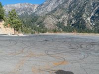 a road with yellow chalk written in the middle of it and a mountain in the back ground