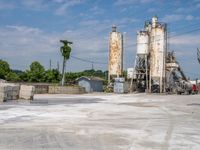 a factory with several cement silos sitting behind it and a forklift truck driving in the front