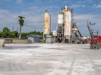 a factory with several cement silos sitting behind it and a forklift truck driving in the front