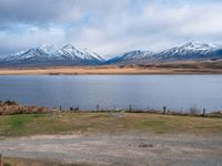 an empty field with mountains in the background in the daytime time with water surrounding it