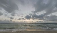 a photo taken of a beach during sunset with some clouds in the sky and water with waves lapping towards it