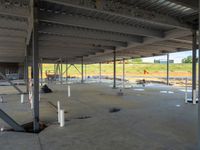 empty industrial space with some steel pipes and workers working on the floor area of it