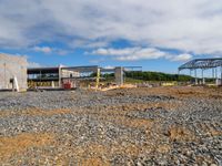 a building being constructed under construction on the other side of the road and gravel parking area