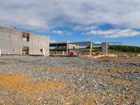 a building being constructed under construction on the other side of the road and gravel parking area