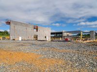 a building being constructed under construction on the other side of the road and gravel parking area