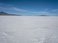 an empty desert with large rocks in the distance and a mountain in the distance across it