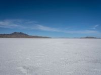 an empty desert with large rocks in the distance and a mountain in the distance across it