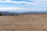 a barren mountain side, a lone person on the bench is overlooking a view of the distant mountains