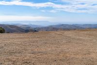 a barren mountain side, a lone person on the bench is overlooking a view of the distant mountains