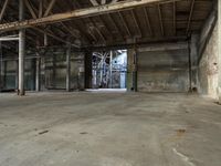 an empty industrial warehouse with exposed beams and large windows in the space outside on a sunny day