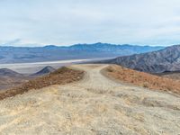 dirt road with mountains on the horizon in the distance at an intersection of hills and desert