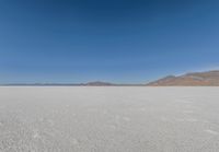 view across vast flat expanse to mountains with sparse sand flooring and sky in the distance