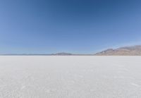 view across vast flat expanse to mountains with sparse sand flooring and sky in the distance