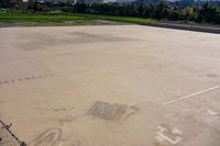 a basketball court in the middle of an open lot with an arrow pointing to it