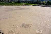 a basketball court in the middle of an open lot with an arrow pointing to it