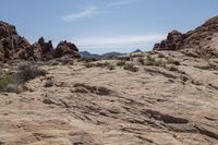 a man sitting on top of a rock formation holding his hand out to a cell phone