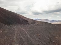 a view of a dirt road with mountains in the back ground and the sky above