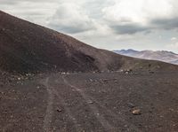 a view of a dirt road with mountains in the back ground and the sky above