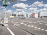 an empty parking lot with a large building in the back ground and a building behind it