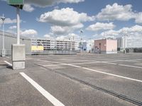 an empty parking lot with a large building in the back ground and a building behind it