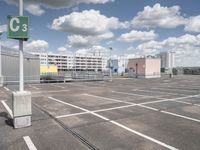 an empty parking lot with a large building in the back ground and a building behind it