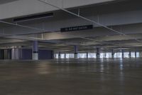 an empty parking garage with some signs hanging off the ceiling of it's sides