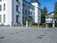 a person riding a bicycle down a sidewalk on a brick road near a white building