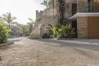 an empty courtyard with a large stone archway in the middle of it and several trees