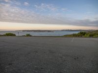 a parking lot with a view of the bay and buildings, along side a street in the distance