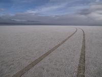 two tires are visible in this large open plain in front of clouds, with mountains in the distance