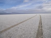 two tires are visible in this large open plain in front of clouds, with mountains in the distance