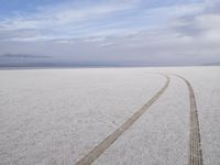 two tires are visible in this large open plain in front of clouds, with mountains in the distance